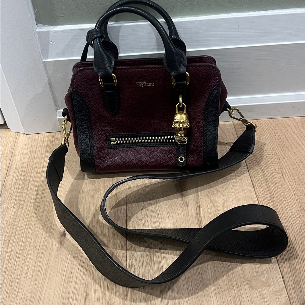 Alexander McQueen Skull Padlock Bag in a burgundy and black color combination.